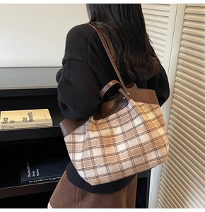 Brown and beige plaid tote bag with leather handles shown in a lifestyle shoulder carry
