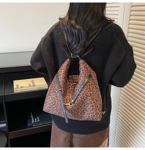 Detail showing versatile leopard print bucket bag worn as a shoulder bag with black strap