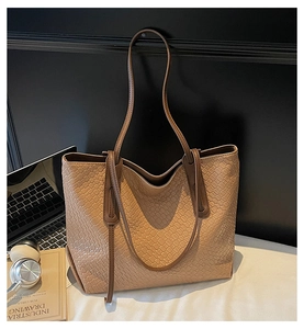 Detailed close-up of woven texture and slender straps on a beige large tote bag