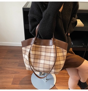 Close-up of vintage brown plaid tote bag featuring leather handles and metal rivet details