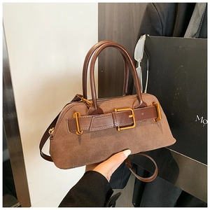 Detail of brown suede patchwork handbag with gold buckle and adjustable shoulder strap