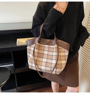 Detailed view of the checkered tote bag with brown faux leather trim and silver rivets