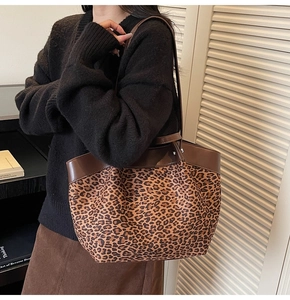 Close-up of leopard print tote bag featuring brown leather trim and sturdy handle detail