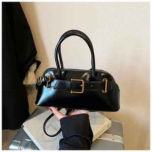 Detailed shot of black patent leather bag with gold buckle and adjustable strap
