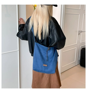 Blue denim tote bag with drawstring closure and vintage leather patch detail