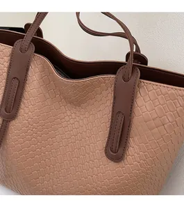 Close-up of woven textured leather tote bag with reinforced stitching and dual-tone finish
