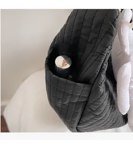 Detail view of the black quilted shoulder bag side pocket with a silver bottle stored