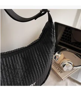 Close-up of black quilted dumpling bag featuring vertical wave texture and woven strap
