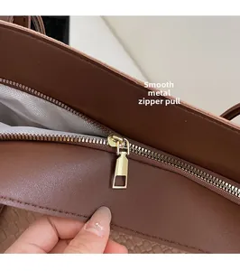 Close-up of smooth gold hardware zipper and textured fabric lining on brown tote bag