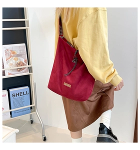 Detail view of burgundy faux suede tote bag with metal logo and chic black white plaid lining