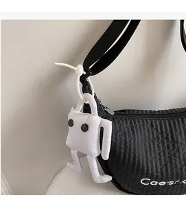 Detail of black quilted shoulder bag featuring a unique white plush doll charm and bead strap