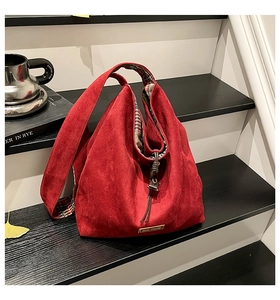 Detail of red suede hobo bag featuring tartan lining and metal tag on base