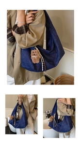 Deep blue denim hobo bag with a plush bear charm shown on a stylish trench coat outfit