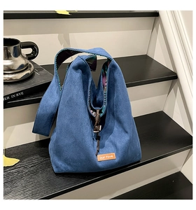 Detail of dark blue vintage hobo bag with drawstring closure and orange leather logo tag