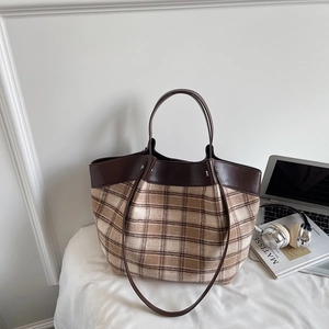 Detailed view of brown checkered tote bag with leather trim and matching shoulder strap