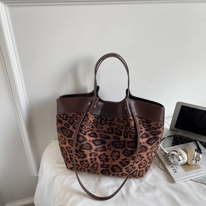 Detail of leopard print tote bag featuring brown leather trim and dual carrying straps
