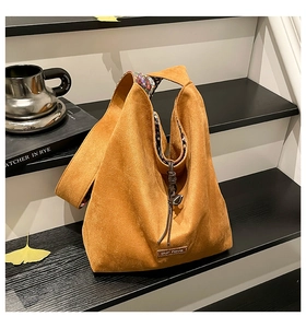 Close-up of camel suede tote bag with floral lining, leather drawstring and brand tag