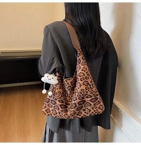 Detail der Leopard-Tasche mit braunem breitem Gurt und weißem Plüsch-Wolken-Anhänger-Design