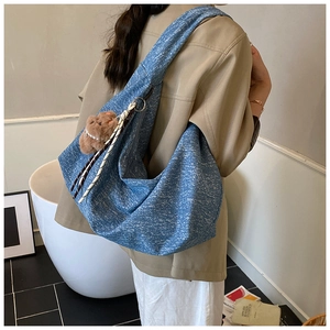 Detail of blue denim hobo bag with plush bear charm and decorative braided rope