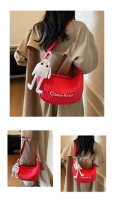 Detail of red quilted dumpling bag with white ghost plush charm and logo embroidery