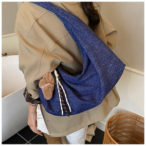 Detail of blue hobo bag showing textured fabric and a cute brown plush pendant