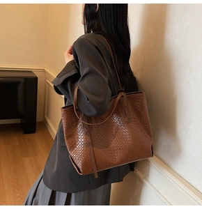 Detail of dark brown woven tote bag showing the wide square Intrecciato weave pattern