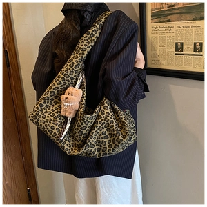 Detail of leopard print tote bag with wide strap and cute brown plush puppy charm