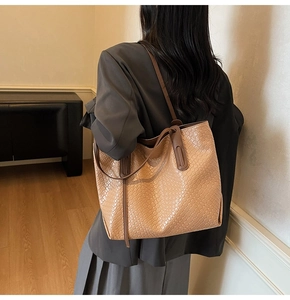 Detailed view of brown woven texture and leather straps on a large tote bag
