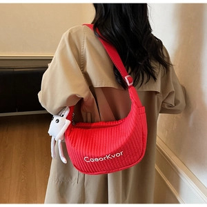 Detail of red quilted dumpling bag featuring white text and a cute rabbit plush charm