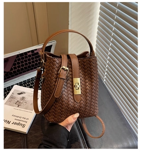Close-up of brown woven bucket bag with gold twist lock and adjustable shoulder strap