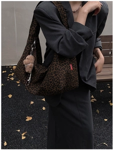 Detail of vintage leopard print tote bag with plush bear charm in outdoor setting