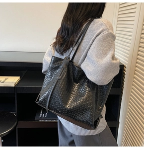 Close-up of black woven leather tote bag shown on model with shoulder strap detail