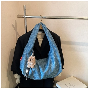 Close-up of blue snowflake texture shoulder bag with cute plush bear charm detail
