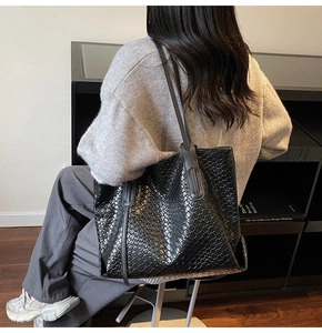 Detail of the intricate black woven texture and leather strap on this large tote bag
