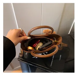 Vue de dessus d'un sac à main marron avec poche zippée, téléphone et cosmétiques