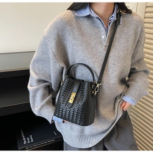 Detailed view of black woven leather bucket bag with a golden turn-lock closure