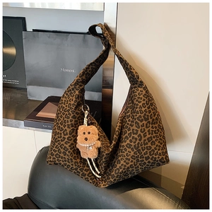 Detail of leopard print shoulder bag with plush bear charm and pearl necklace accent