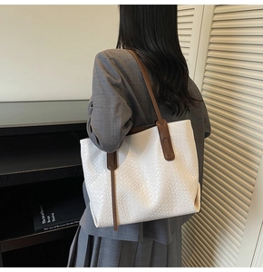 Close-up of woven leather texture on the white tote bag with contrast brown strap