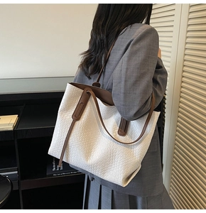 Detail showing the white woven texture and dark brown leather handle of the tote bag