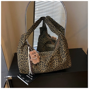 Detail view of leopard print tote bag with zipper and brown teddy bear plush charm
