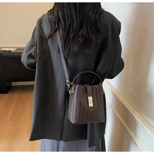 Detail of dark brown woven bucket bag featuring metal twist lock and fine texture
