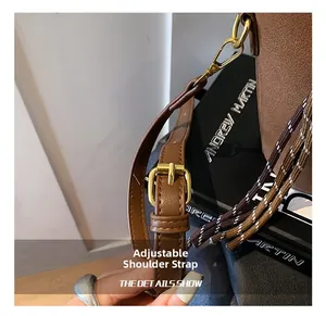 Détail de la bandoulière réglable et de la boucle dorée sur le sac seau en daim marron