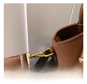 Gros plan sur les crochets dorés et le grain du cuir de ce sac seau marron chic