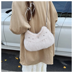 Detailed shot of white faux fur shoulder bag with silver star rivets and metal chain strap