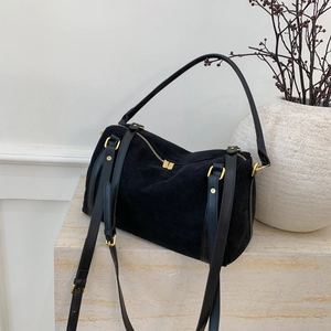 Détail du sac Boston en daim noir avec ferrures dorées sur une surface en pierre