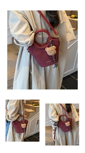 Détail du sac seau bordeaux avec texture mate, poignée ronde et pendentif ours