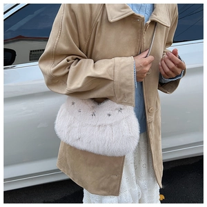 Close-up of fluffy white faux fur shoulder bag with silver star-shaped metal studs