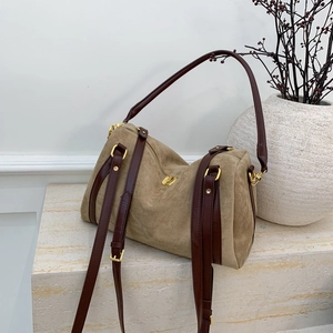 Détail du sac Boston montrant le daim kaki et la bandoulière en cuir brun sur marbre