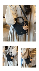 Détail du sac seau noir mat avec poignée ronde et pendentif en forme d'ours