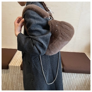 Détail d'un sac à bandoulière en fausse fourrure marron avec chaîne sur un manteau